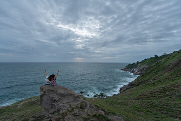 Fototapeta na wymiar Couple sitting at the cape watching beautiful view of ocean. Romantic
