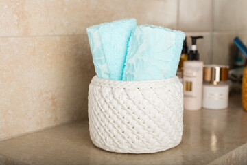 Wicker basket with rolled up blue towels. Clean towel in the bathroom. Hygiene and healthy lifestyle concept
