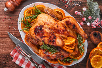 Roasted or baked whole chicken with rosemary and oranges, homemade for Christmas traditional family dinner on an old wooden rustic table. Top view with copy space.