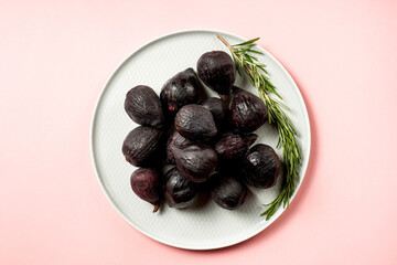 Fresh ripe figs in a plate. Beautiful blue violet fruit on pastel pink background. Healthy Mediterranean fig fruit. Copy space for text. Top view. Vegan concept
