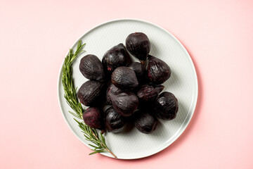 Fresh ripe figs in a plate. Beautiful blue violet fruit on pastel pink background. Healthy Mediterranean fig fruit. Copy space for text. Top view. Vegan concept