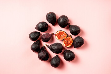 Fresh ripe figs in a plate. Beautiful blue violet fruit on pastel pink background. Healthy Mediterranean fig fruit. Copy space for text. Top view. Vegan concept