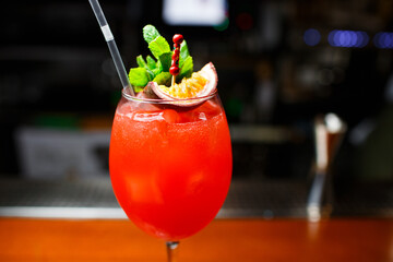 red cocktail with champagne passion fruit and mint leaves on dark background