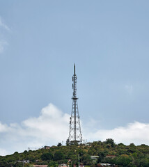 Telecommunication tower over town buildings and houses. High frequency receiver on the island with summer sky. Telephone and television antenna near living apartments.
