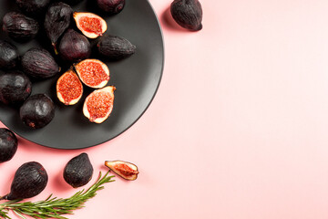Fresh ripe figs in a plate. Beautiful blue violet fruit on pastel pink background. Healthy Mediterranean fig fruit. Copy space for text. Top view. Vegan concept