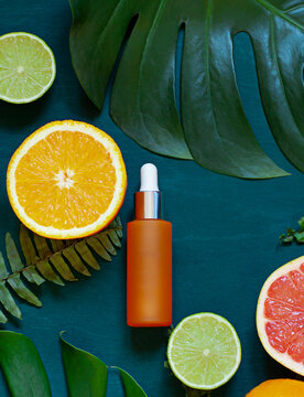 Cosmetic flat lay with vitamin C serum and citrus on the back wooden background. Top view	