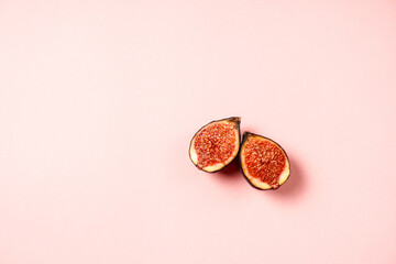 Fresh ripe figs in a plate. Beautiful blue violet fruit on pastel pink background. Healthy Mediterranean fig fruit. Copy space for text. Top view. Vegan concept