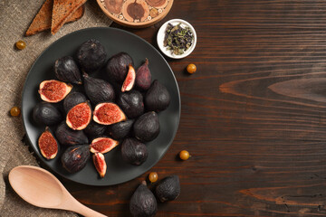 Delicious ripe figs, spice and bread served on dark wooden board, flat lay. Tasty figs freshly cut in half. Healthy food concept. Top view.