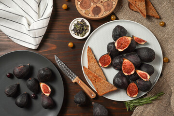 Delicious ripe figs, spice and bread served on dark wooden board, flat lay. Tasty figs freshly cut in half. Healthy food concept. Top view.