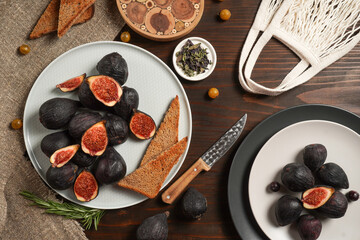 Delicious ripe figs, spice and bread served on dark wooden board, flat lay. Tasty figs freshly cut in half. Healthy food concept. Top view.