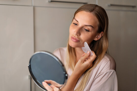 Portrait of beautiful female pretty 30s woman posing indoor have healthy well-kept skin. Style and beauty, skin care concept, daily routine for face. Holding guasha massager.