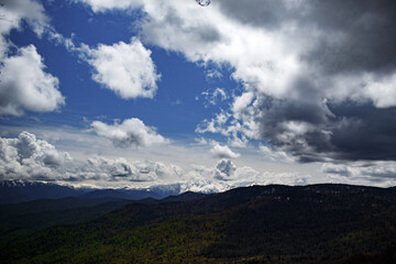 view of snow-capped mountains and massive clouds against a blue sky