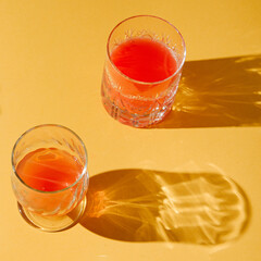 Authentic summer layout made with glasses of drinks on a pastel yellow background. Creative minimal concept.