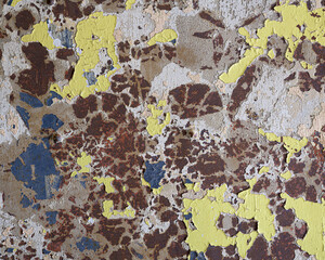Peeling brown and yellow paint on old wall forms abstract textured background