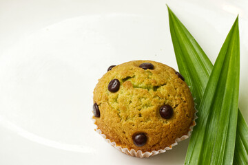 Pandan cupcakes on a white plate with pandan leaves on the side.