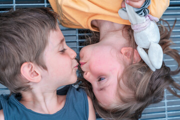 portrait of twins boys and girls are kissing lying on a metal grate