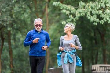 Smiling senior couple jogging in the park. Sports activities for elderly people.