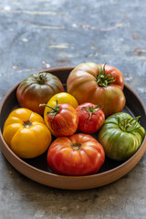 Heirloom tomatoes in black bowl on rustic metal surface