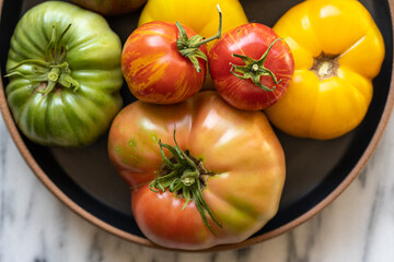 Heirloom tomatoes in black bowl on marble counter