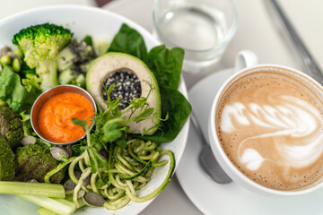 Close up image of tasty green vegan avocado bowl and latte art coffee. healthy vegan lifestyle.