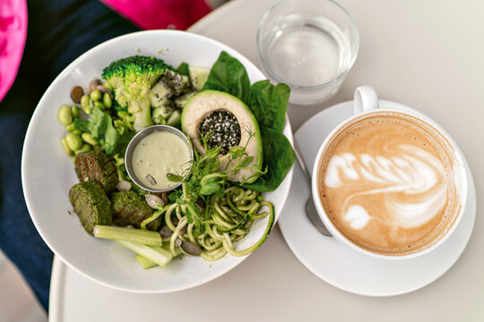 Close up image of tasty green vegan avocado bowl and latte art coffee. healthy vegan lifestyle.