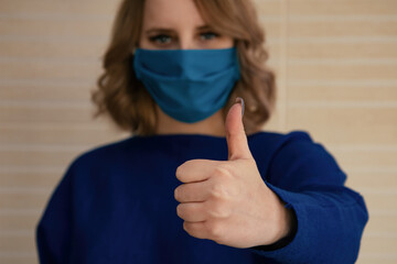 A beautiful girl in a mask shows gestures with her hands. A woman in a blue sweater. Viruses and...