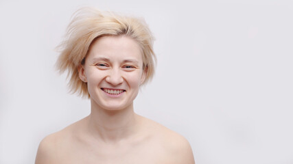 An attractive blonde topless model with short hair posing for the camera. Carefree young girl smiling. Isolated girl over white background studio shot. Flawless skin concept.