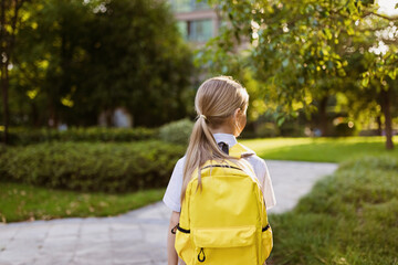 Back to school. Little girl with yellow backpack from elementary school outdoor. Kid going learn new things 1th september after end Coronavirus covid-19 quarantine and self isolation 