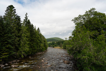 View of River Dee with surrounding forest on banks and hill in distance. Taken from Balmoral Bridge, Balmoral Estate, Scotland.