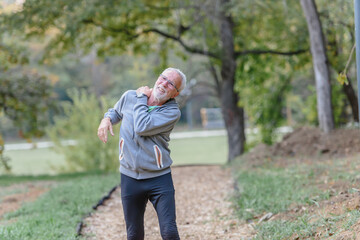 Senior older man jogging in the park having shoulder injury