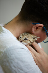 Non-binary person cuddles very young rescue kitten