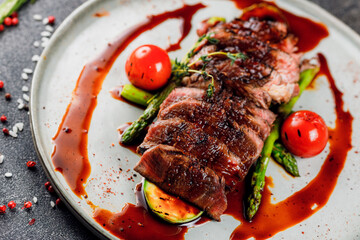 filet mignon steak chateaubrian with grilled vegetables and sauce on a white plate
