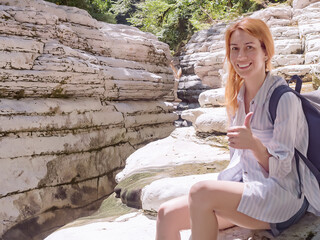 Fototapeta premium Smiling tourist showing thumbs up while sitting on the rocks against the background of white canyons