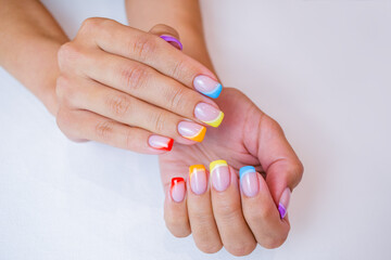 Hands of a young woman with a manicure. The nails are covered with gel polish with colored French.