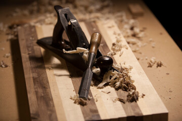 Antique hand planer and chisel on top of a butcher block surrounded by wood shavings. - obrazy, fototapety, plakaty