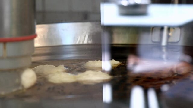 Close up of press machine making lokma fried dough, traditional Greek sweet food. 
