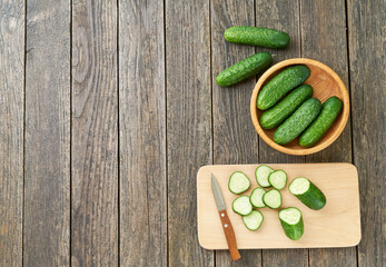 Fototapeta na wymiar Whole and sliced ripe cucumbers on a cutting board, top view.