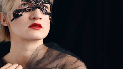 A model dressed in a masquerade ball costume for the fancy costume party. Wearing A Venetian Masquerade Mask and red lipstick. Closeup headshot. Mysterious girl wearing a lace Masquerade mask.