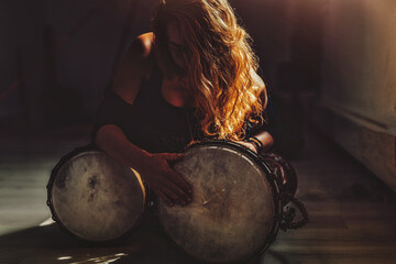 beautiful young girl playing on djembe.