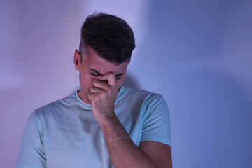 Young Hispanic male with hand on face with worried gesture on white background.