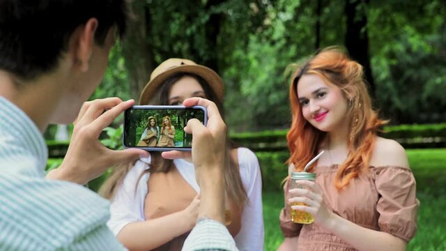 A guy takes pictures of girls on the phone in the summer in nature, close-up