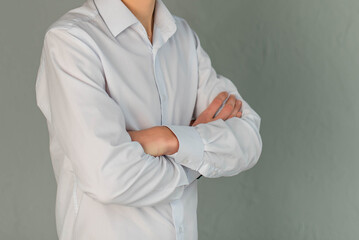 A young man in a white shirt and stands on a gray background.