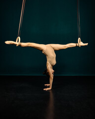 Experimental art Portrait of a gymnast in a leotard with gymnastic rings. Standing on hands in a twine, legs stuck into rings