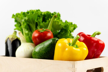 Fresh vegetables in a wooden box. Lettuce, peppers, tomatoes, avocado, eggplant, onions in close-up. Delivery and healthy food concept