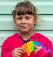 Teenage girl posing with a children's toy near the wall. The flexible touch push-bubble fidget toy...