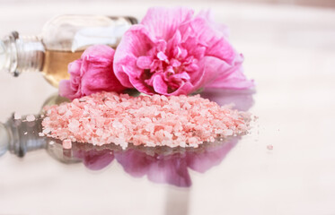 Sea salt, pink flowers,  essential aroma oil in a little glass bottle on white background.  Body care, Spa background . Copy space, stock photo