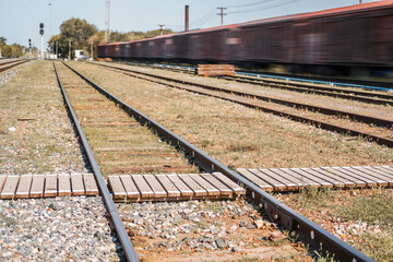 Obraz premium Pedestrian wooden crossing over the railway in the daytime. The place where people cross the railroad is safe.