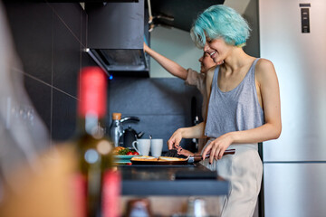 Side View Young Lesbian Couple Family Enjoy Morning Together, Cooking Preparing Food, Laughing and Having Fun In Modern Kitchen At Home, In Domestic Clothes. LGBT, lesbian relationships. Copy space