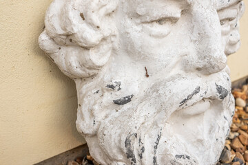 Fototapeta premium Unidentifiable decorative male face garden ornament leaning against a wall