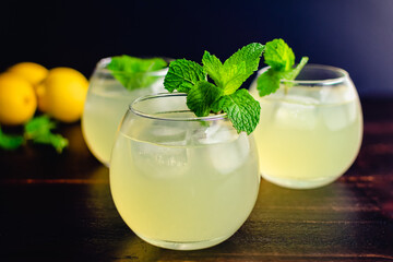 Glasses Limonata Turkish Lemonade with a Mint Garnish: Lemonade with a mint garnish on a wooden table